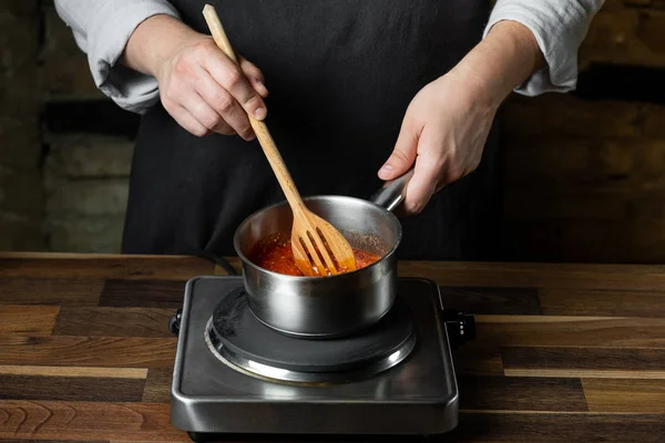 Siyah arka plan kopya metin tarifi mutfak göreve adımları Şef ellerimden metal tencerede pişirme domates sosu.