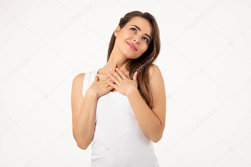 young smiling woman gesturing with hands touching her neck standing on white background