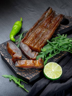 Deniz balığı yeşil kireç ve roka koyu arka plan üzerinde füme