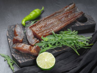 Deniz balığı yeşil kireç ve roka koyu arka plan üzerinde füme