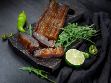 Yeşil biber ve koyu arka plan üzerinde roka ile deniz balık füme