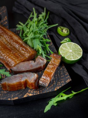 Yeşil biber ve koyu arka plan üzerinde roka ile deniz balık füme