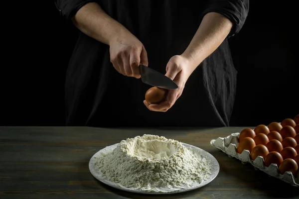 Chef hands cooking dough over wooden background. Food concept