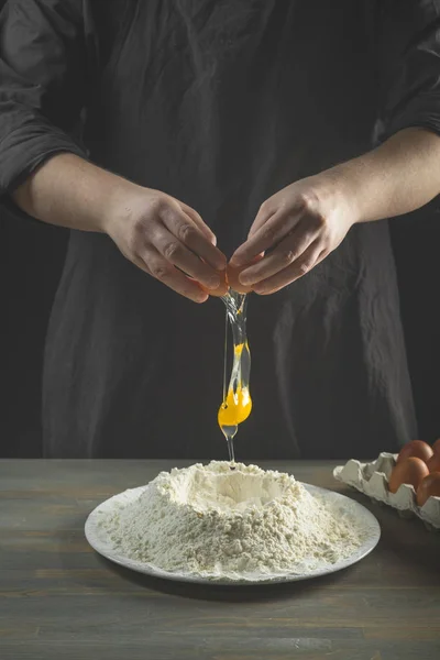 Chef hands cooking dough over wooden background. Food concept