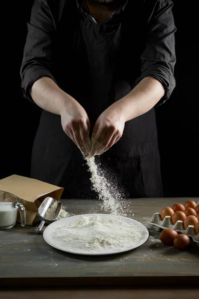 Chef hands cooking dough over wooden background. Food concept