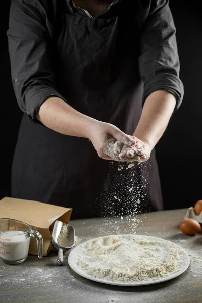 Chef hands cooking dough over wooden background. Food concept