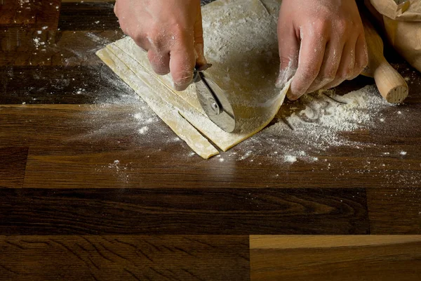 シェフ パスタ麺棒 紙袋とみじん切りパスタの小麦粉の木製テーブルの上の生地を切断 家庭料理の概念 — ストック写真