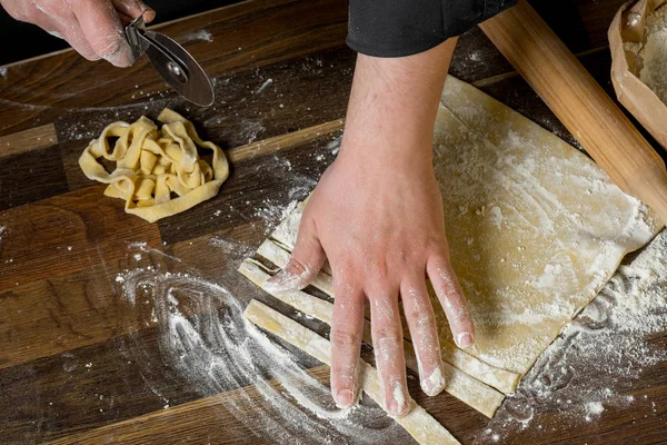 シェフ パスタ麺棒 紙袋とみじん切りパスタの小麦粉の木製テーブルの上の生地を切断 上面ビュー 家庭料理の概念 — ストック写真