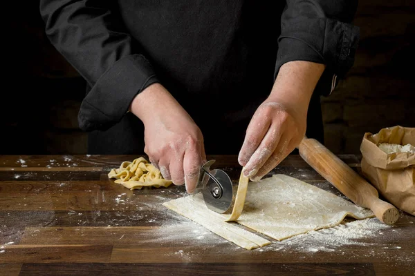 シェフ パスタ麺棒 紙袋とみじん切りパスタの小麦粉の木製テーブルの上の生地を切断 家庭料理の概念 — ストック写真