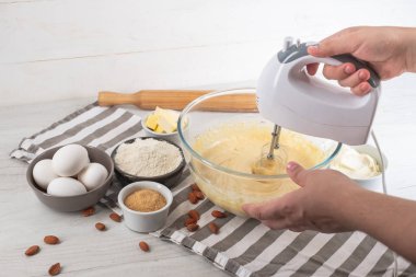 Chef malzemeler mutfak masasında yemeklerle tatlı cheesecake yemek elinde karıştırıcılı