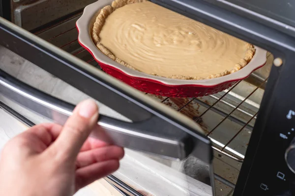 Chef baking sweet cheesecake in modern oven