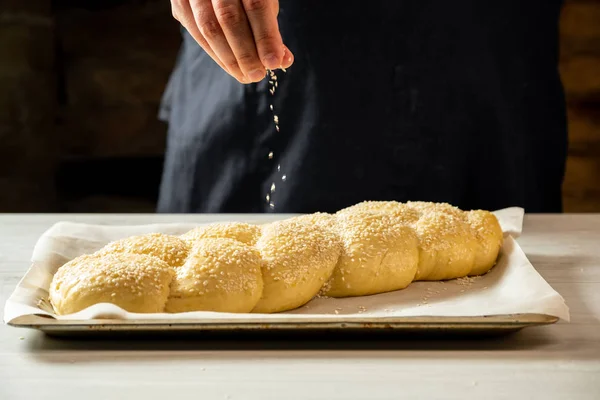 Мужчина Пекарь Посыпать Сырой Халлы Еврейский Хлеб Кунжутом Семян — стоковое фото