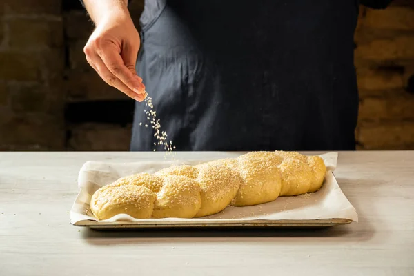 Férfi Baker Locsolás Nyers Barhesz Zsidó Kenyér Szezámmag — Stock Fotó