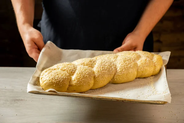 面包师手持烤盘与原始 Challah 传统犹太面包 — 图库照片