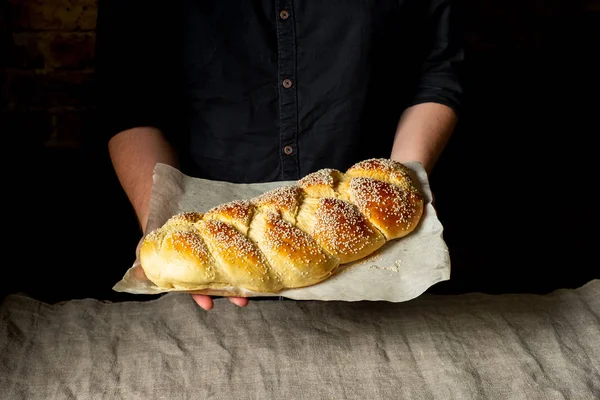 面包师傅拿着新鲜出炉的 Challah 传统犹太面包在纸上 — 图库照片