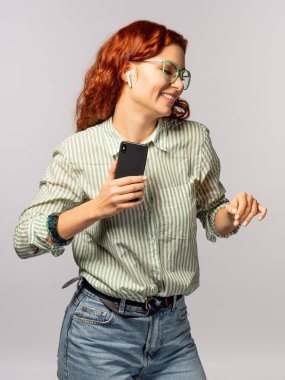 Smartphone ışık arka plan üzerinde tutan earpods olan mutlu kadın