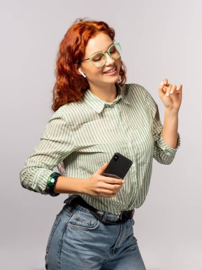 Smartphone ışık arka plan üzerinde tutan earpods olan mutlu kadın