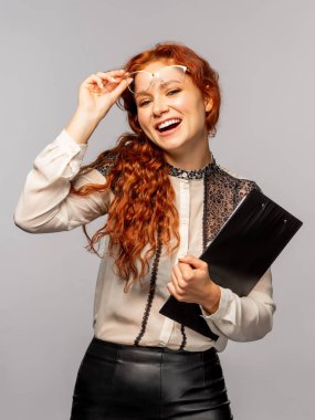 Karton tutan ve gri arka plan üzerinde poz genç Kıvırcık Kızıl saçlı kadın