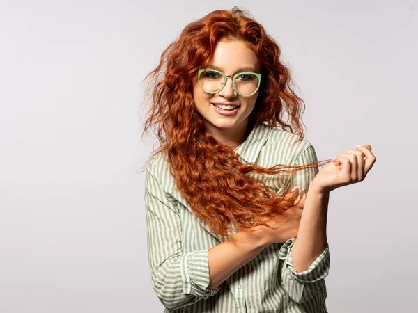 Portrait of cheerful young curly woman on light background
