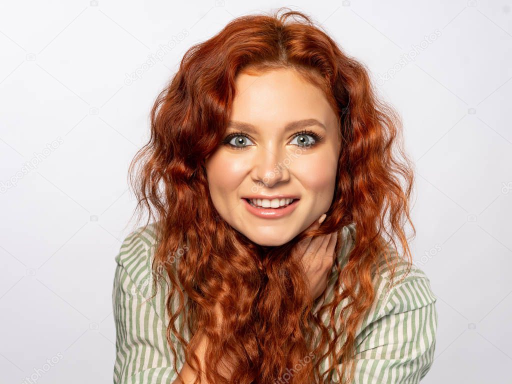Portrait of cheerful young curly woman on light background