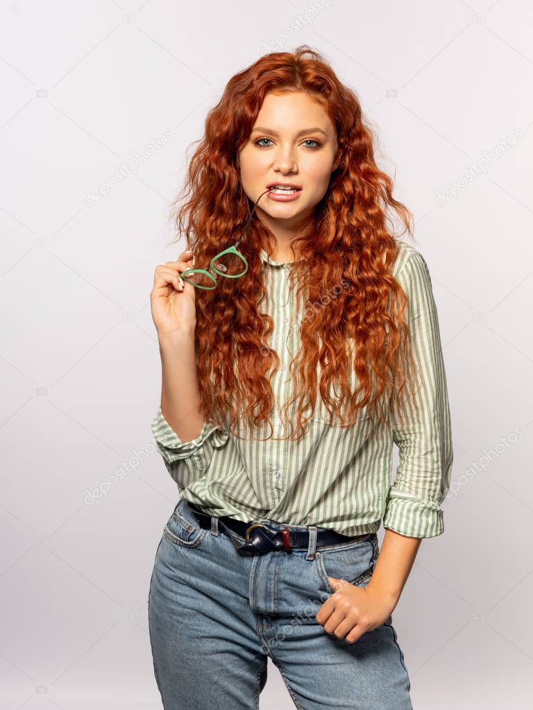 Young stylish woman with eyeglasses posing on light background