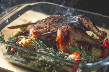 Fırında bütün tavuk sebze ve biberiye ile yanan görünümü Kapat 