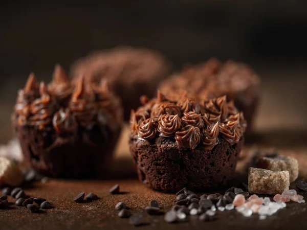 Fresh chocolate cupcakes with salted caramel and brown sugar cubes on dark stone background