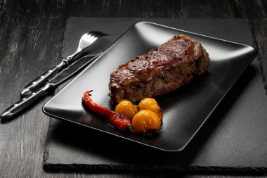 Sarı domates ve biber siyah plaka üzerinde taze pişmiş sığır eti