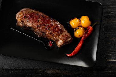 Sarı domates ve biber siyah plaka üzerinde taze pişmiş sığır eti