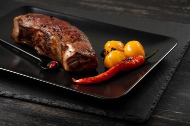 Sarı domates ve biber siyah plaka üzerinde taze pişmiş sığır eti