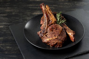 Ahşap arka plan üzerinde siyah plaka üzerinde Izgara Dana kaburga pişmiş taze