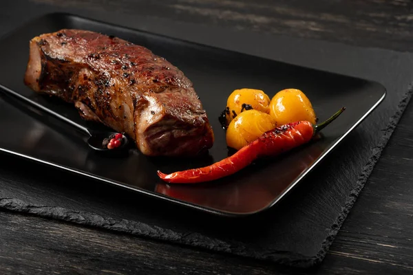 Sarı domates ve biber siyah plaka üzerinde taze pişmiş sığır eti