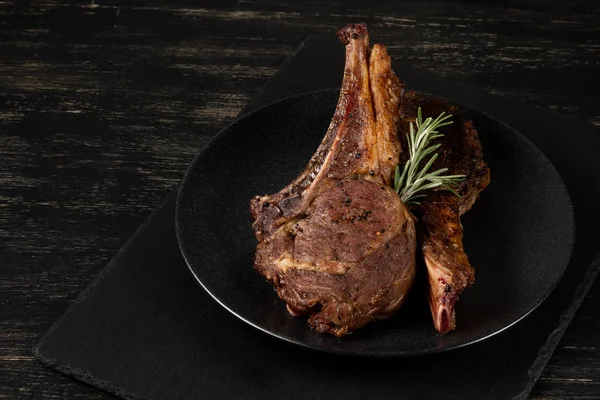 Ahşap arka plan üzerinde siyah plaka üzerinde Izgara Dana kaburga pişmiş taze