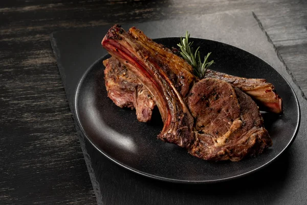 Ahşap arka plan üzerinde siyah plaka üzerinde Izgara Dana kaburga pişmiş taze