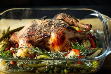 Fırında bütün tavuk sebze ve biberiye güveç çanağı içinde yanan