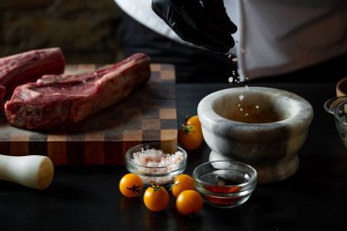 Şef Domuz kaburga çeşitli baharatlar ve tuz ahşap tahta üzerinde hazırlanıyor