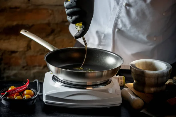 Chef pouring oil in frying pan for cooking dinner