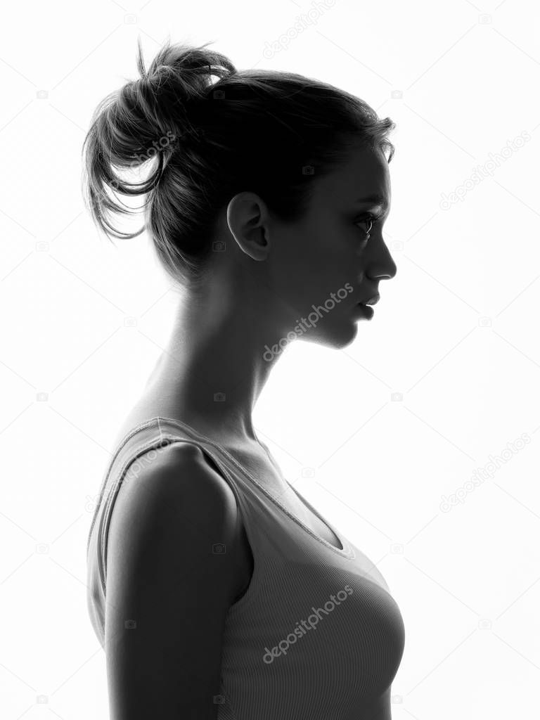 Young woman with natural makeup posing against bright light on white background