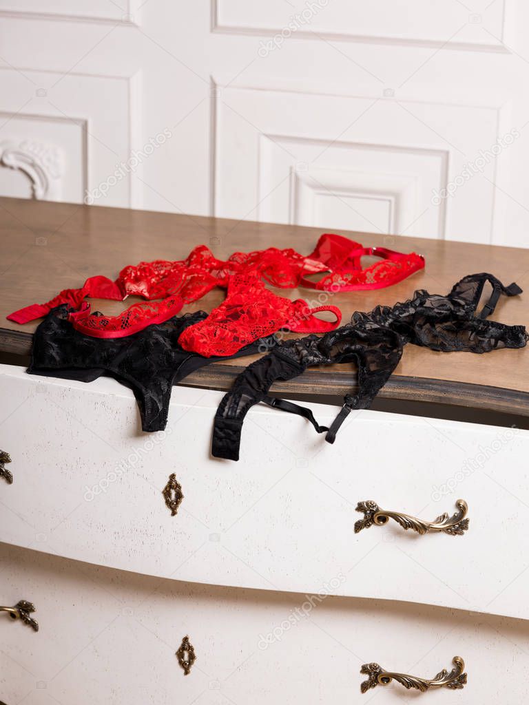 Red and black lace lingerie on white luxury vintage commode 