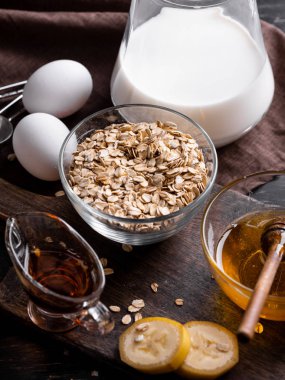 Kase kuru yulaf gevreği, yumurta, süt, muz dilimleri ve ahşap tahta üzerinde taze organik bal kabı tam