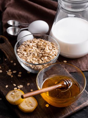 Kase kuru yulaf gevreği, yumurta, süt, muz dilimleri ve ahşap tahta üzerinde taze organik bal kabı tam