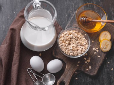 Kase kuru yulaf gevreği, yumurta, süt, muz dilimleri ve ahşap tahta üzerinde taze organik bal kabı tam