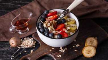 Çilek, kivi ve ahşap tahta üzerinde badem yaprakları ile süslenmiş taze yulaf ezmesi