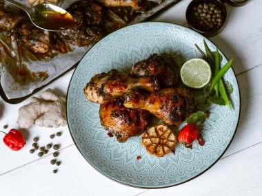 Taze pişmiş tavuk budu ile kireç dilim, otlar ve sarımsak mavi tabakta servis