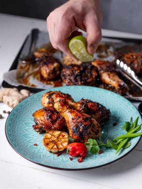 Chef sprinkling lime juice on spice chicken legs  clipart