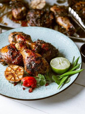 Taze pişmiş tavuk budu ile kireç dilim, otlar ve sarımsak mavi tabakta servis