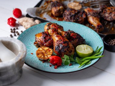 Taze pişmiş tavuk budu ile kireç dilim, otlar ve sarımsak mavi tabakta servis