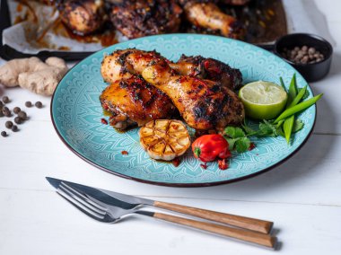 Taze pişmiş tavuk budu ile kireç dilim, otlar ve sarımsak mavi tabakta servis