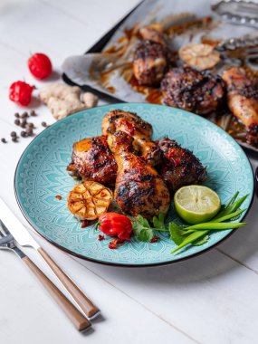 Taze pişmiş tavuk budu ile kireç dilim, otlar ve sarımsak mavi tabakta servis