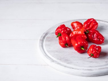 Olgun kırmızı biber görünümü şeffaf cam tepsi üzerinde beyaz ahşap masa üzerinde kapat